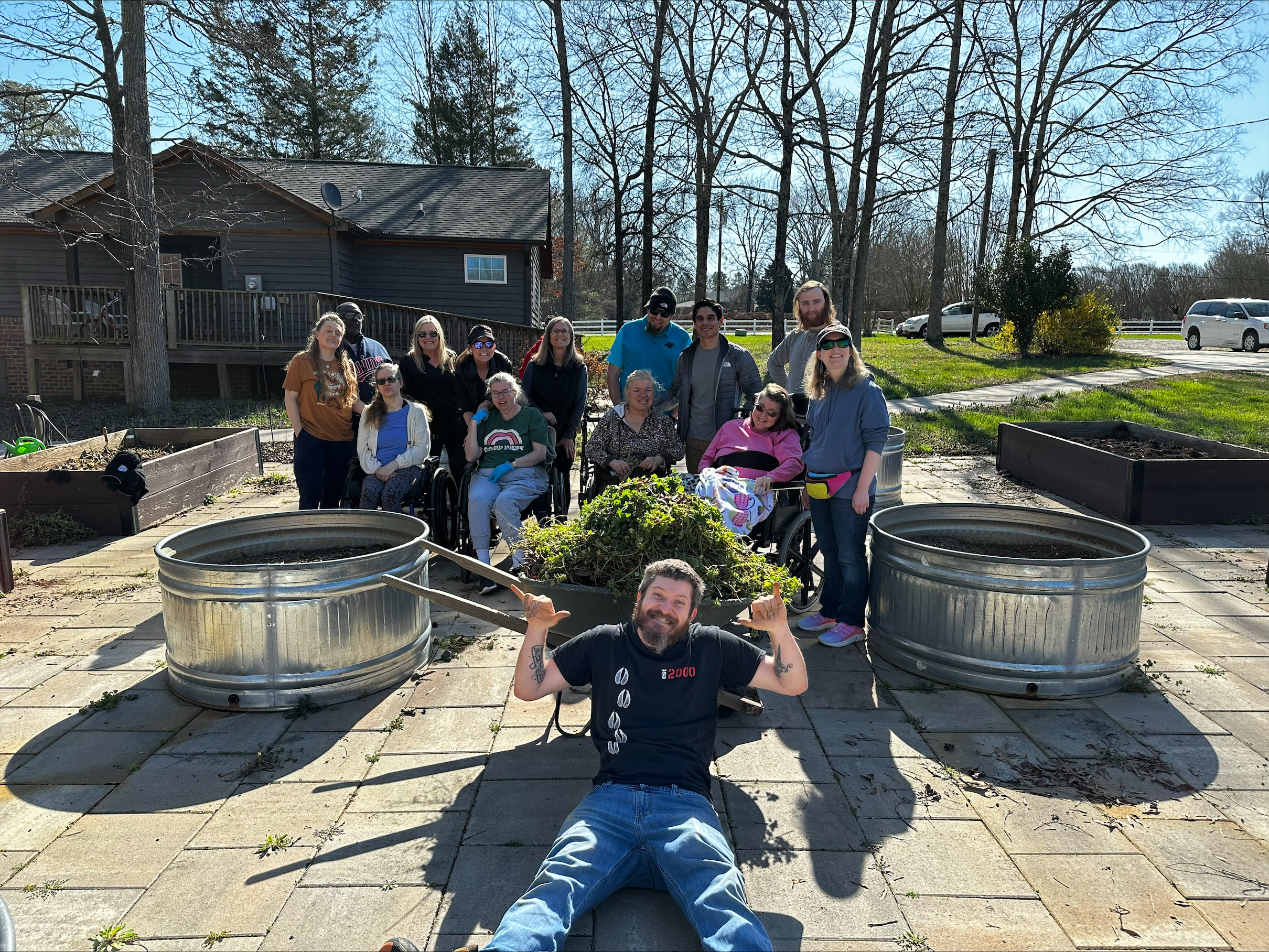 man sitting in front of a wheelbarrow in front of a group of people