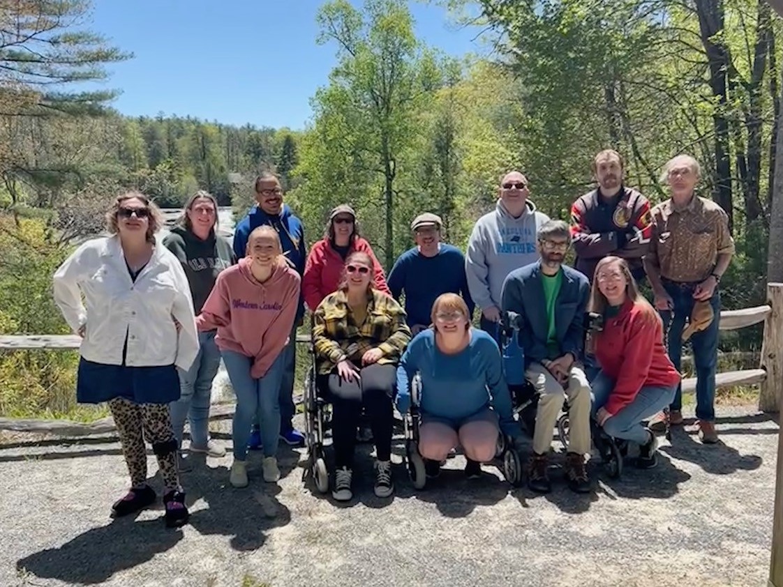 group of people smiling in front of forest overlook view